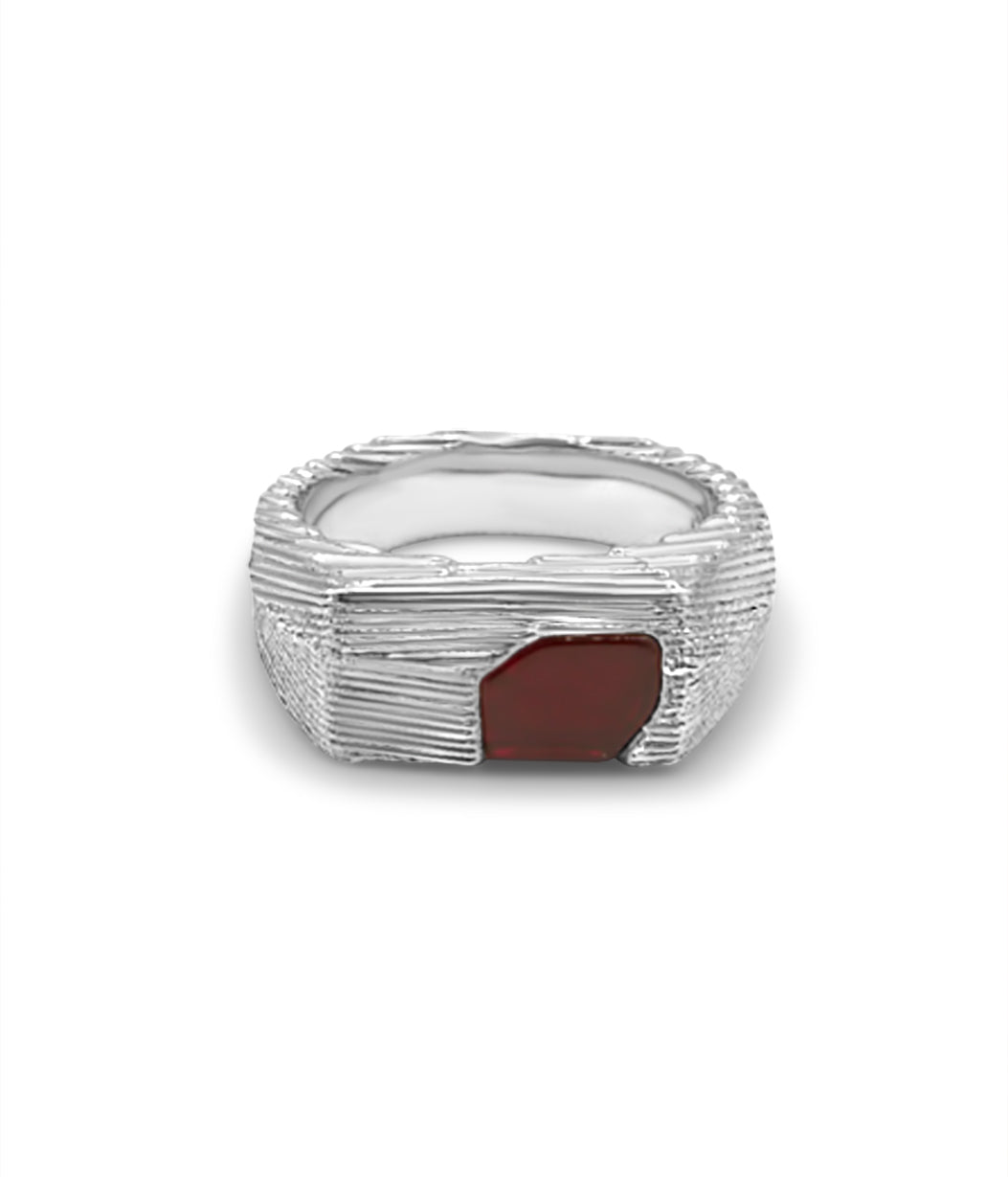Silver ring with a red stone on a white background