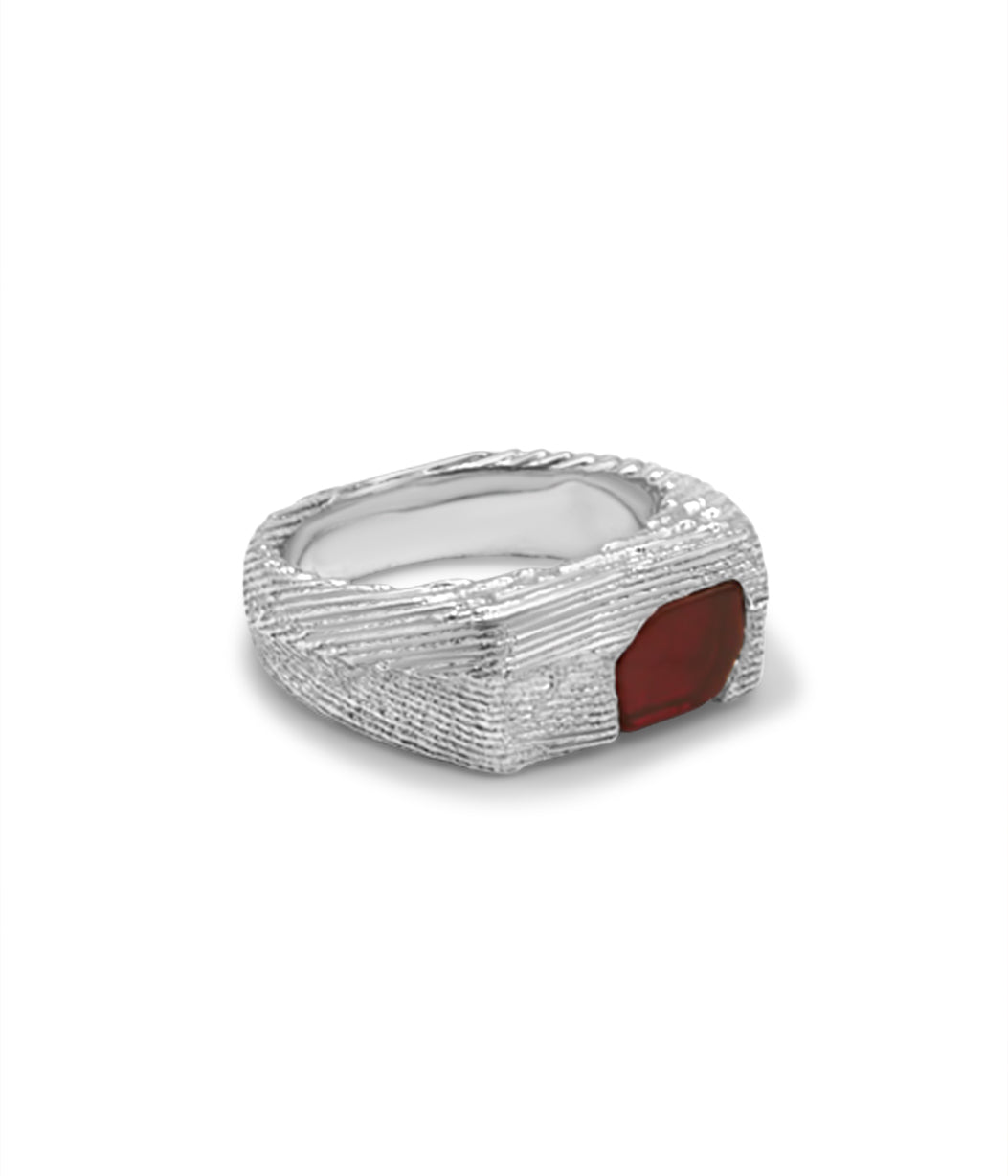 Silver ring with a red stone on a white background