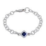 A silver chain bracelet featuring a central diamond-shaped bezel set with a deep blue square gemstone, photographed on a solid white background.