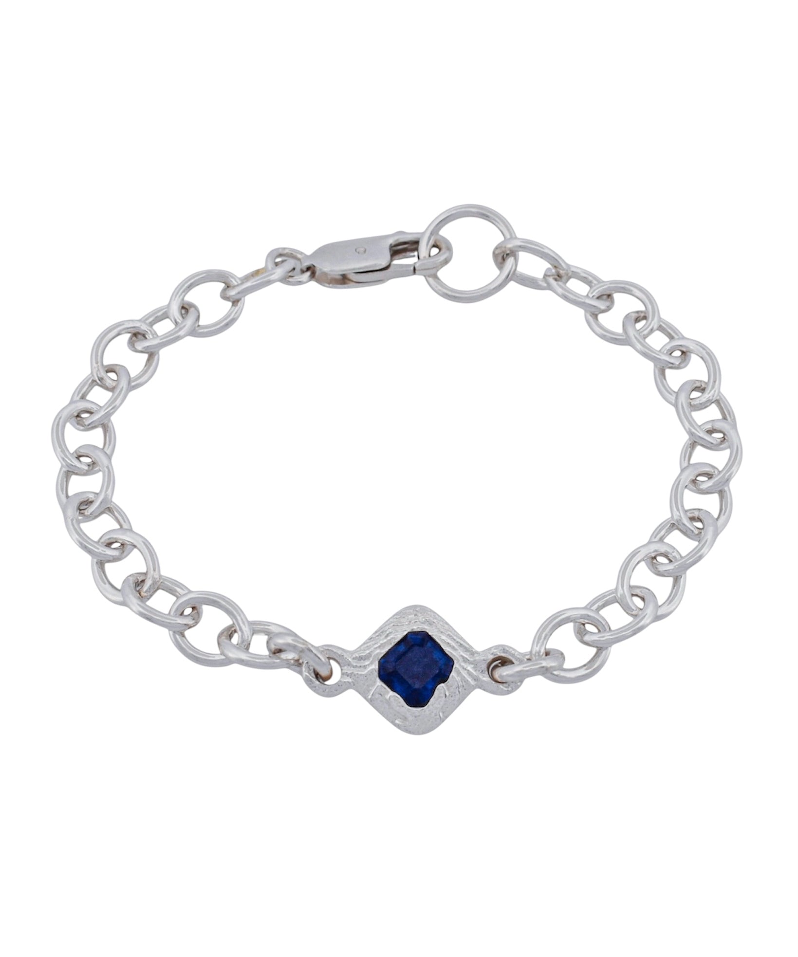 A silver chain bracelet featuring a central diamond-shaped bezel set with a deep blue square gemstone, photographed on a solid white background.