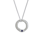 A silver pendant necklace featuring a textured circular ring with a small dark blue gemstone accent, suspended from a delicate silver chain against a plain white background.