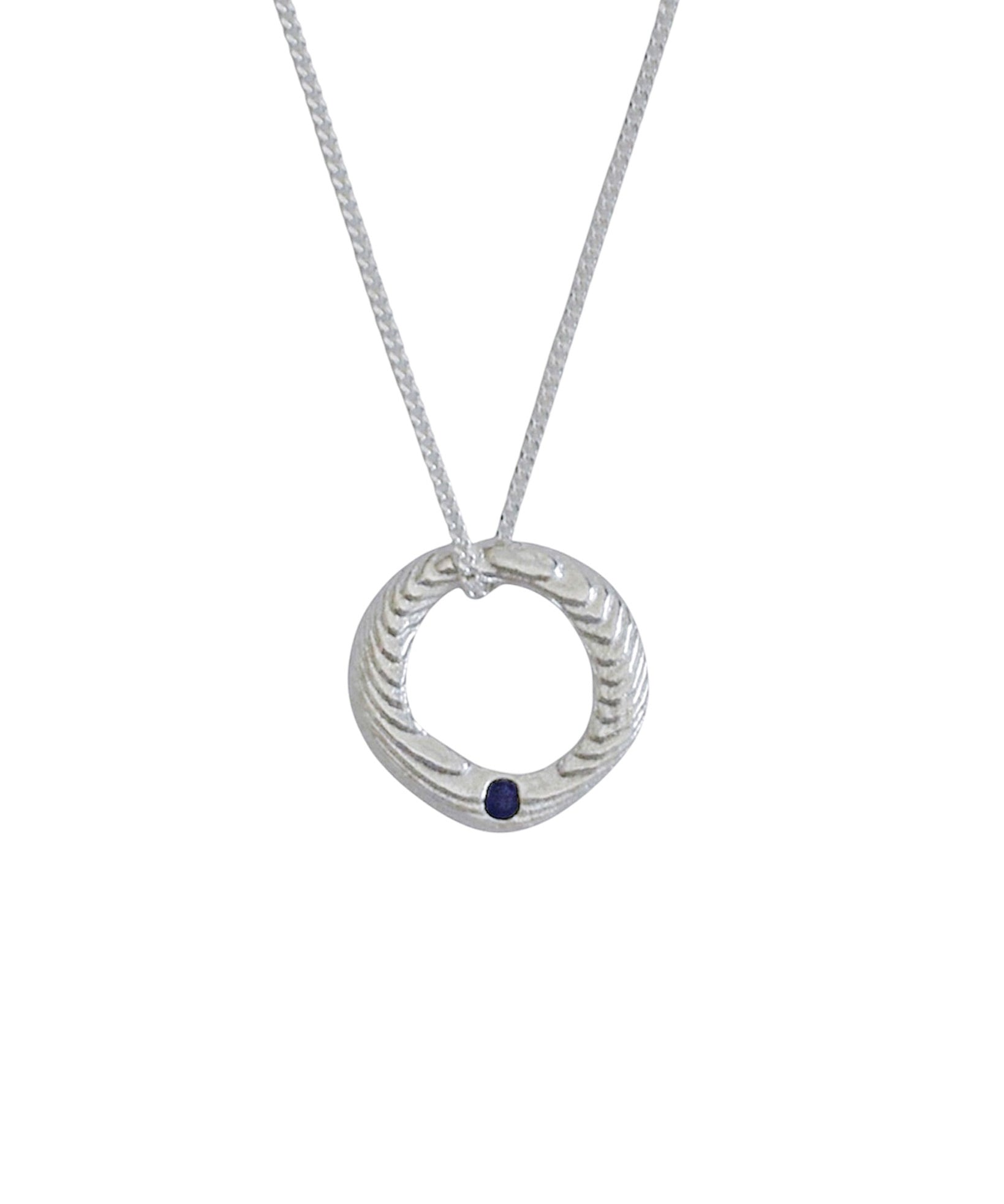 A silver pendant necklace featuring a textured circular ring with a small dark blue gemstone accent, suspended from a delicate silver chain against a plain white background.