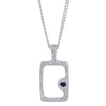 A silver pendant necklace featuring a textured rectangular frame with a small dark heart-shaped stone set on the lower right side, suspended from a silver chain against a plain white background.
