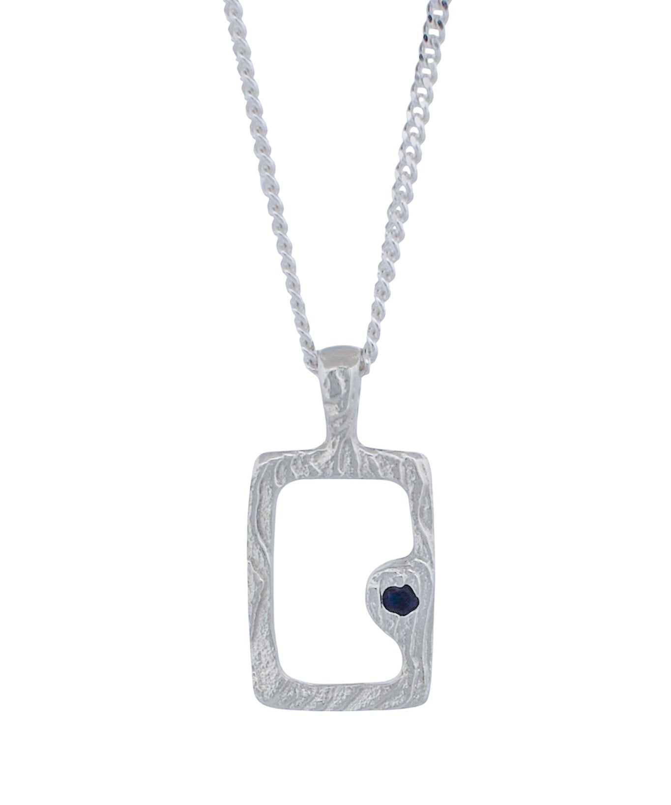 A silver pendant necklace featuring a textured rectangular frame with a small dark heart-shaped stone set on the lower right side, suspended from a silver chain against a plain white background.