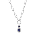 A silver paperclip chain necklace with a teardrop-shaped silver pendant featuring a small round dark blue gemstone above a larger oval dark blue gemstone, set against a plain white background.