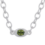 A silver link chain necklace featuring an oval silver pendant with a faceted green gemstone, shown against a plain white background.