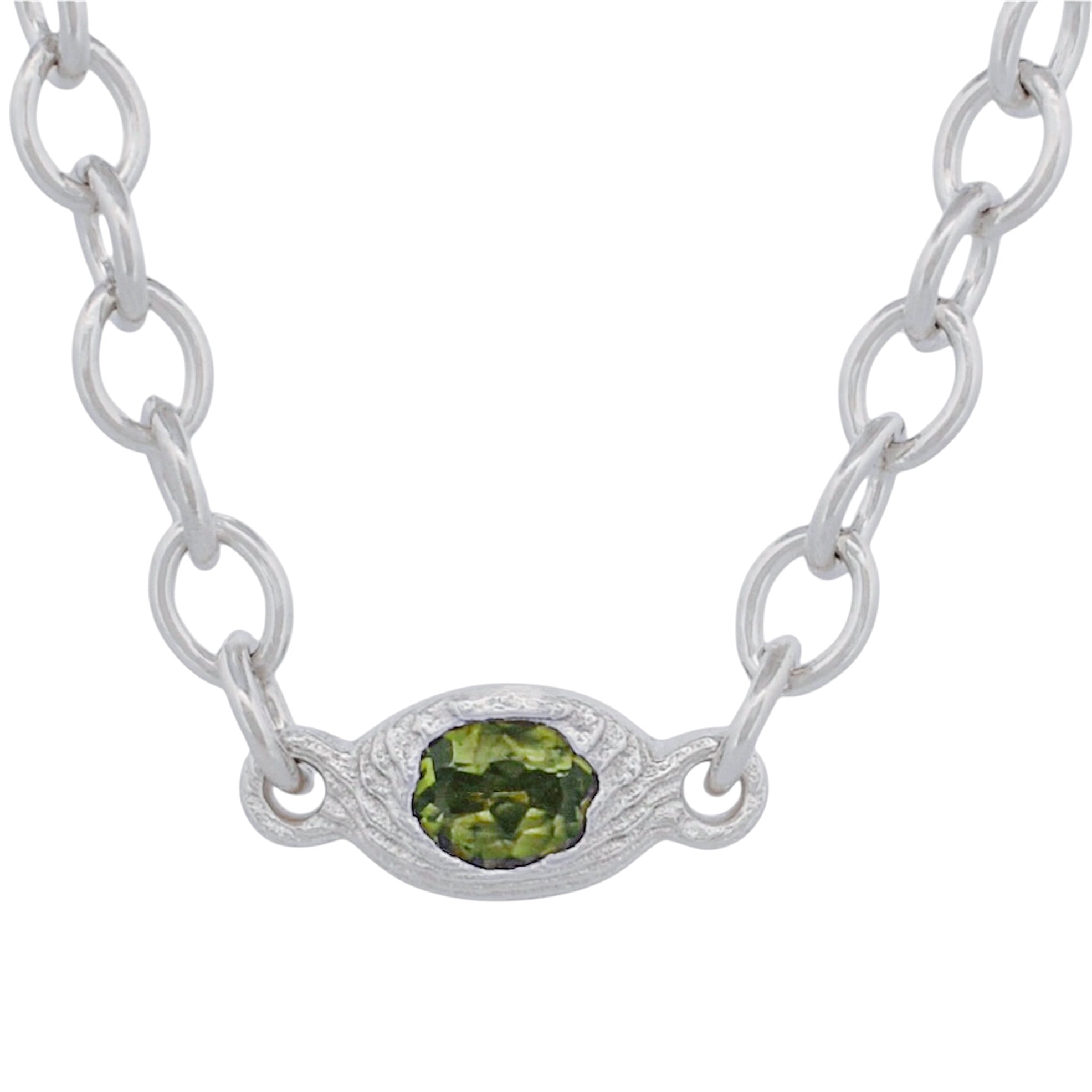 A silver link chain necklace featuring an oval silver pendant with a faceted green gemstone, shown against a plain white background.