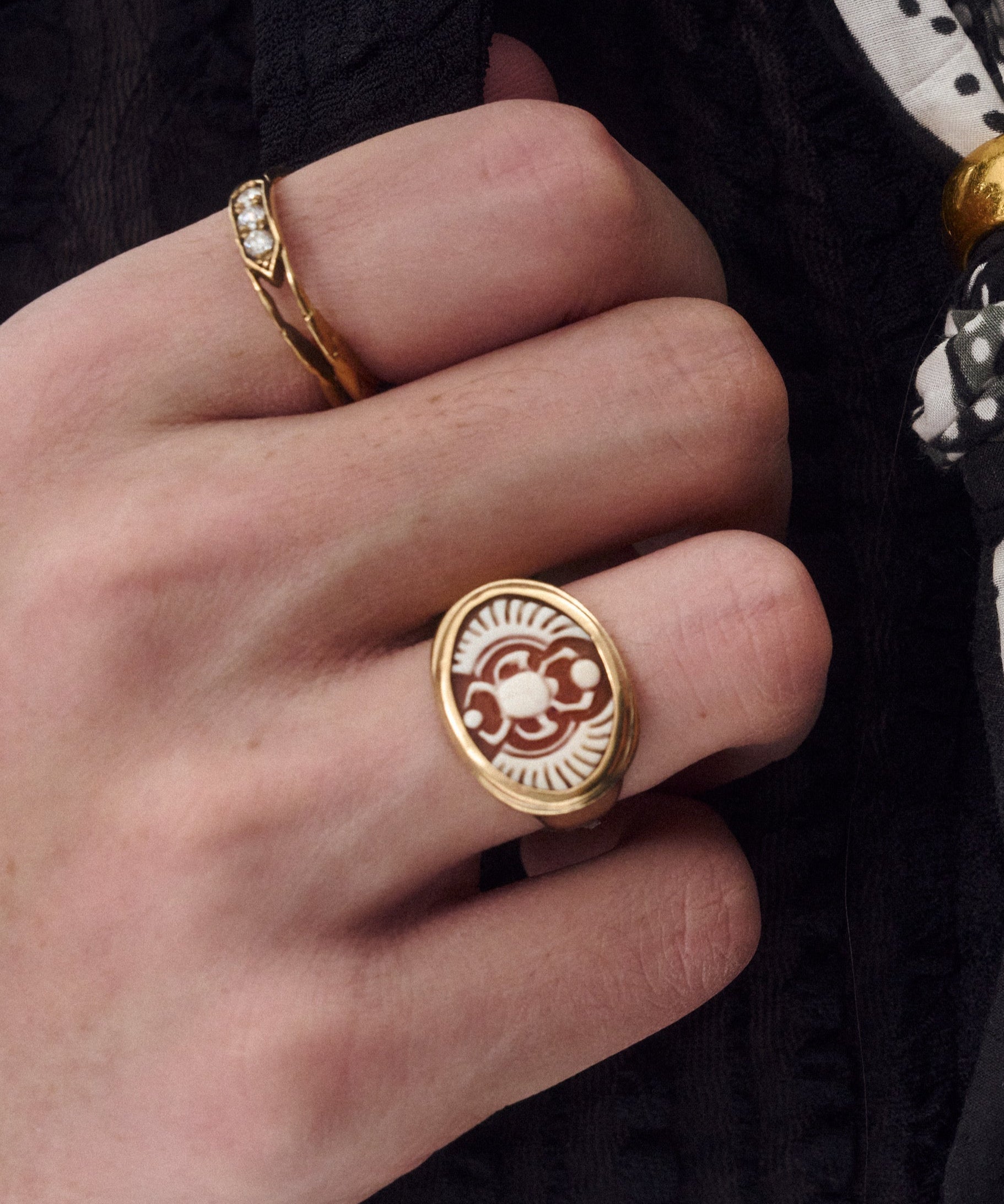 Close-up of hands wearing multiple gold rings with different designs on a dark background.