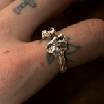 Gold ring with a unique design worn on a finger with tattoos.
