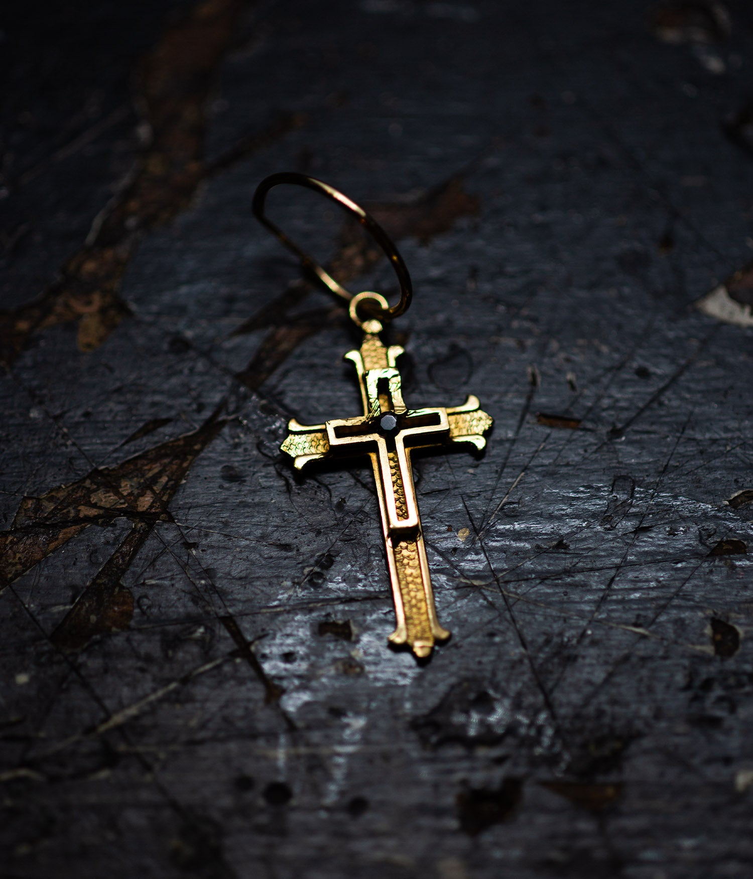 Gold cross pendant on a dark textured surface