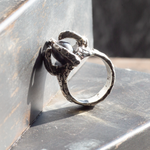 Silver ring with intricate design on a metallic surface