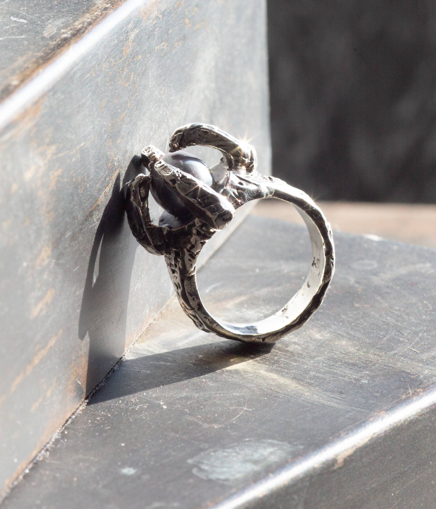 Silver ring with intricate design on a metallic surface
