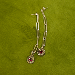 Silver chain earrings with red gemstones on a green background
