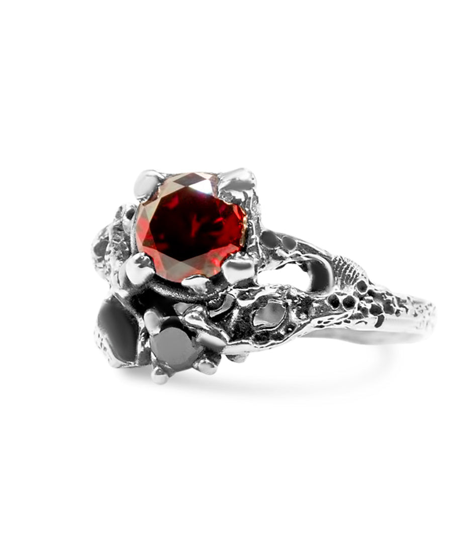Silver ring with a red gemstone on a white background