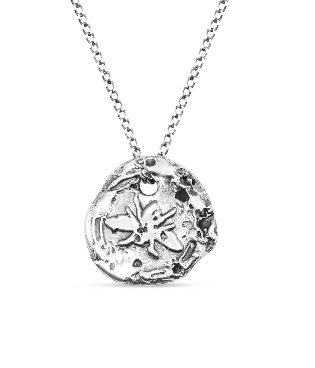 Silver necklace with a round pendant featuring a floral design on a white background