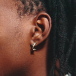 Close-up of an ear with a gold earring and braided hair.