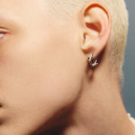 Close-up of a person wearing a silver earring with a blurred background