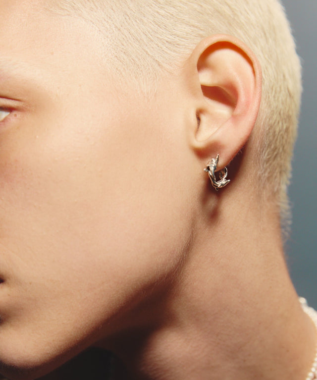 Close-up of a person wearing a silver earring with a blurred background