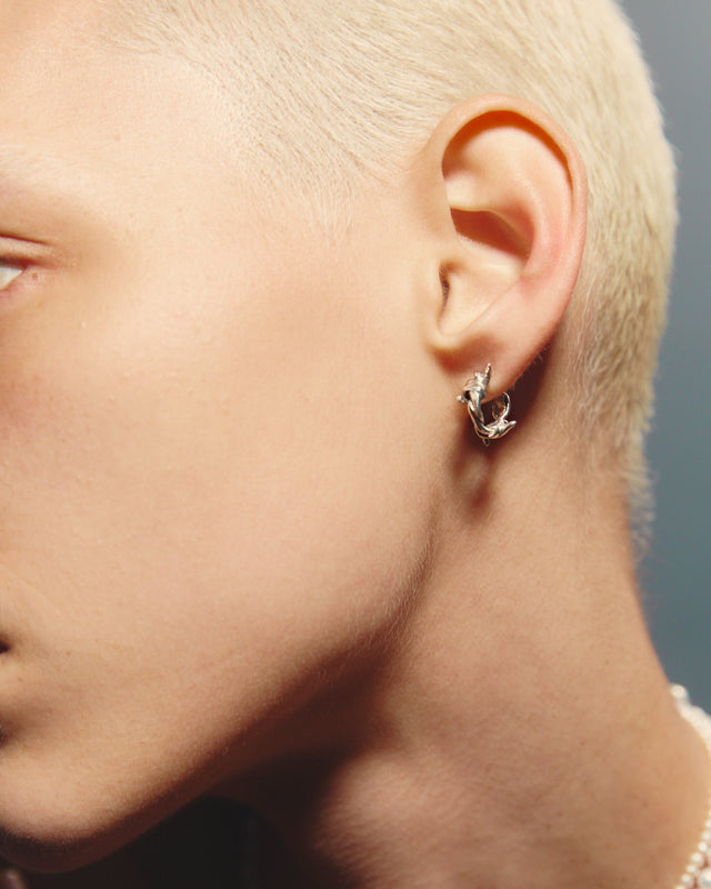 Close-up of a person wearing a silver earring with a blurred background