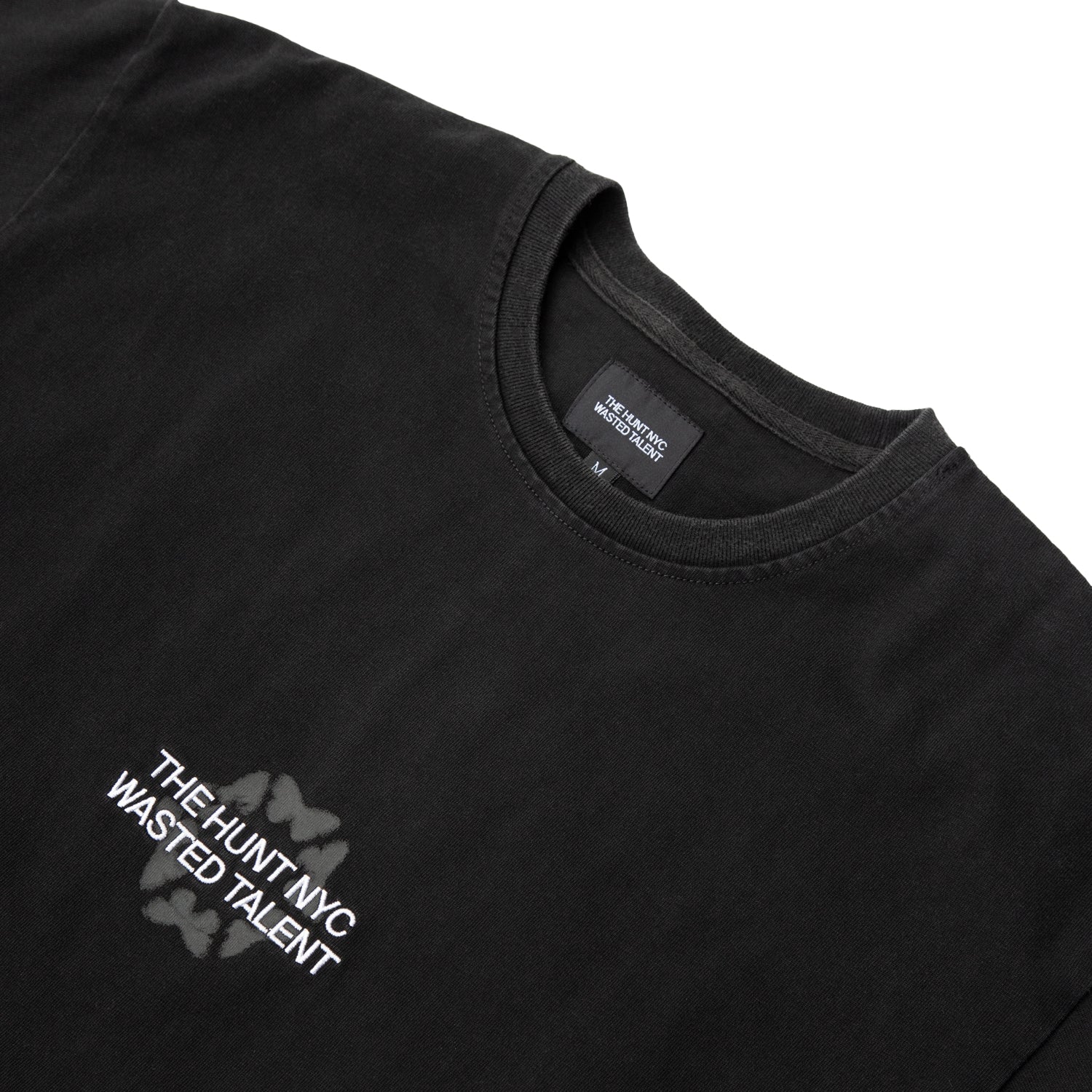 Zoomed view of collar and chest print on THE HUNT NYC x Wasted Talent black tee — butterfly motif and monochrome branding.