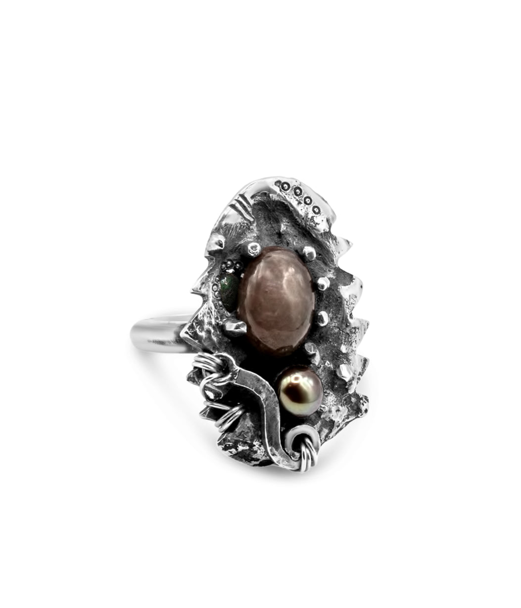 Silver ring with a central brown stone on a white background