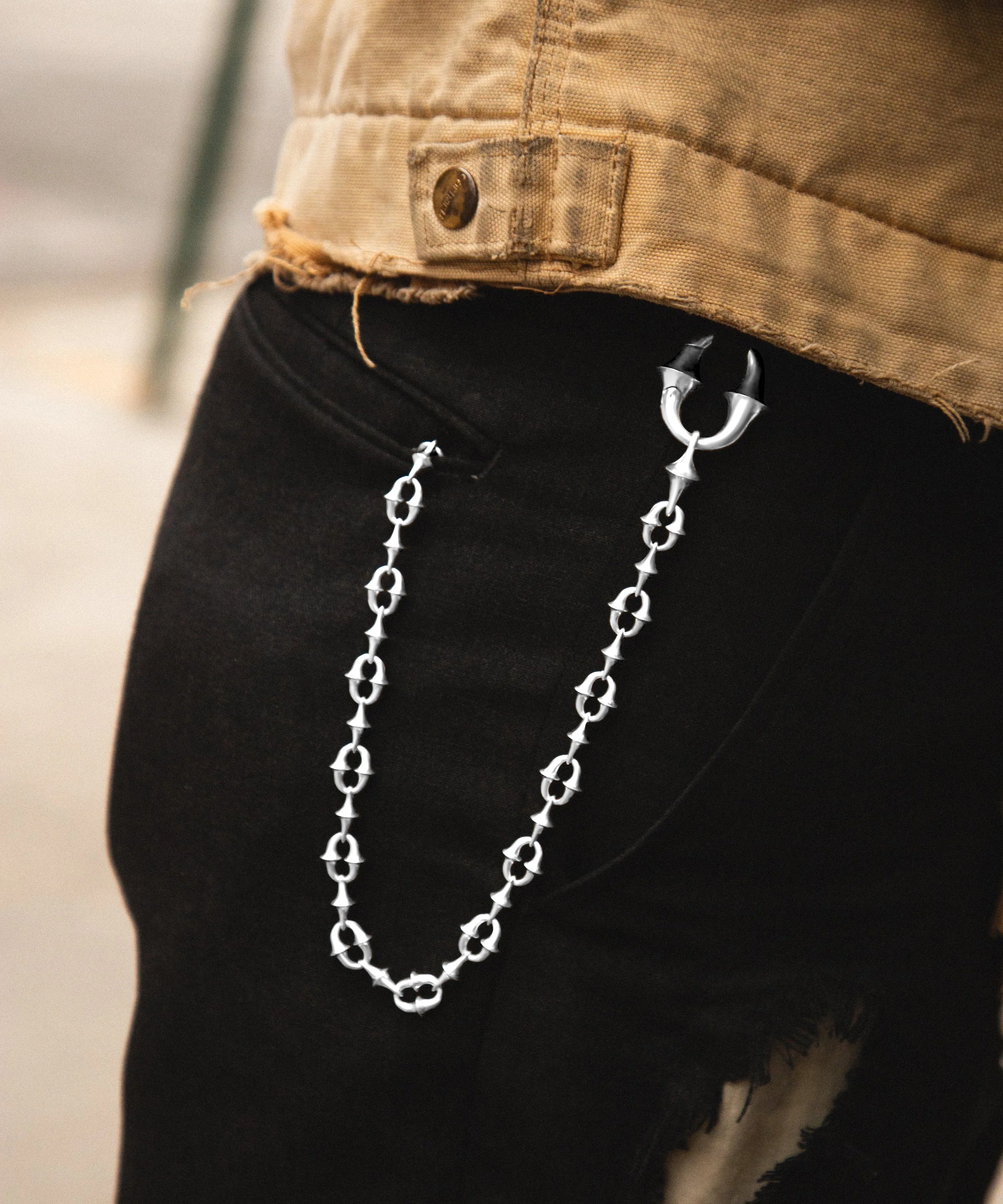 Silver chain hanging from a pocket on black pants with a blurred background