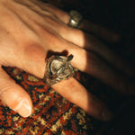 Close-up of a hand wearing a ring on a patterned fabric background