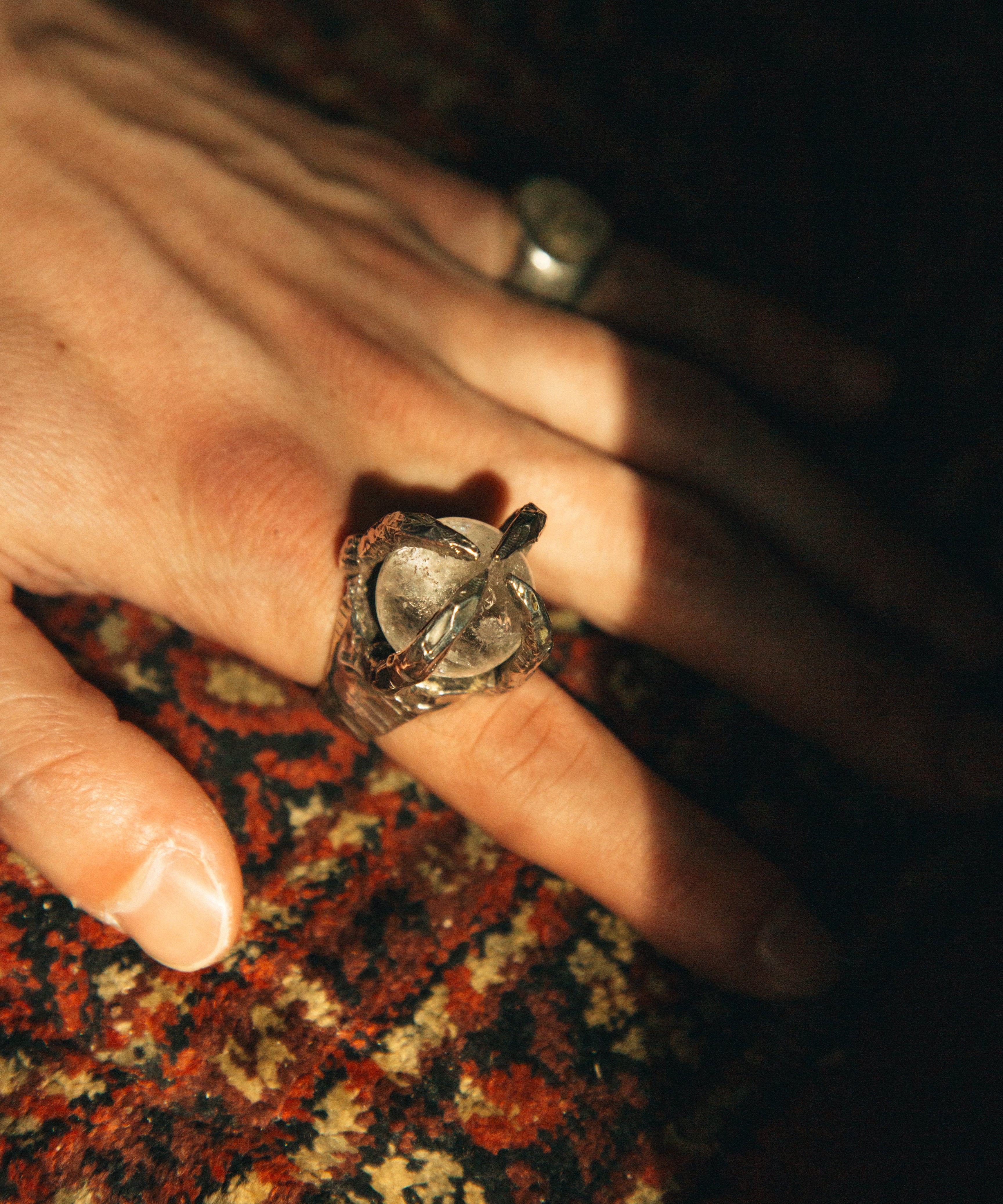 Close-up of a hand wearing a ring on a patterned fabric background