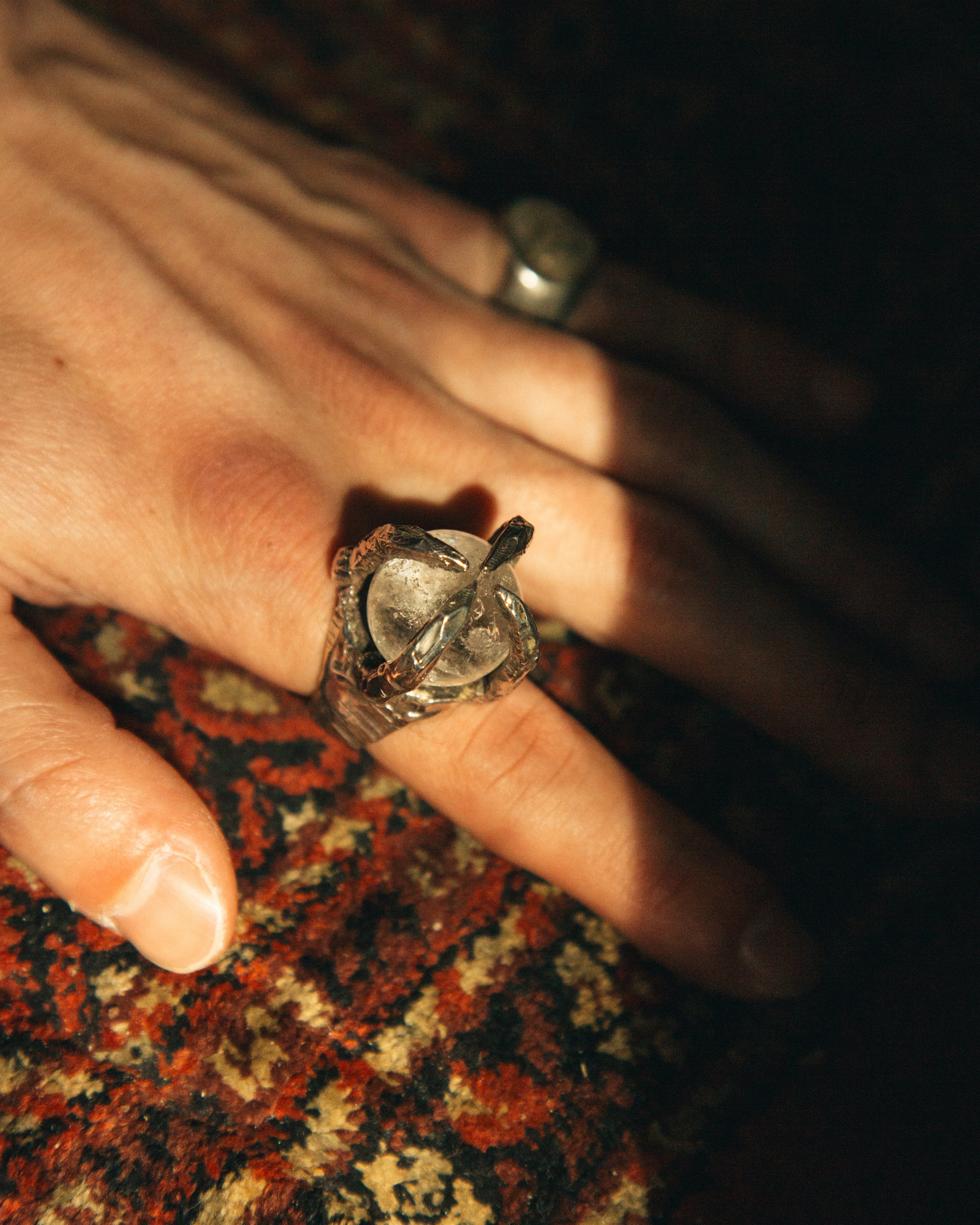 Close-up of a hand wearing a ring on a patterned fabric background