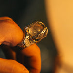 Close-up of a hand holding a decorative ring with a dark background