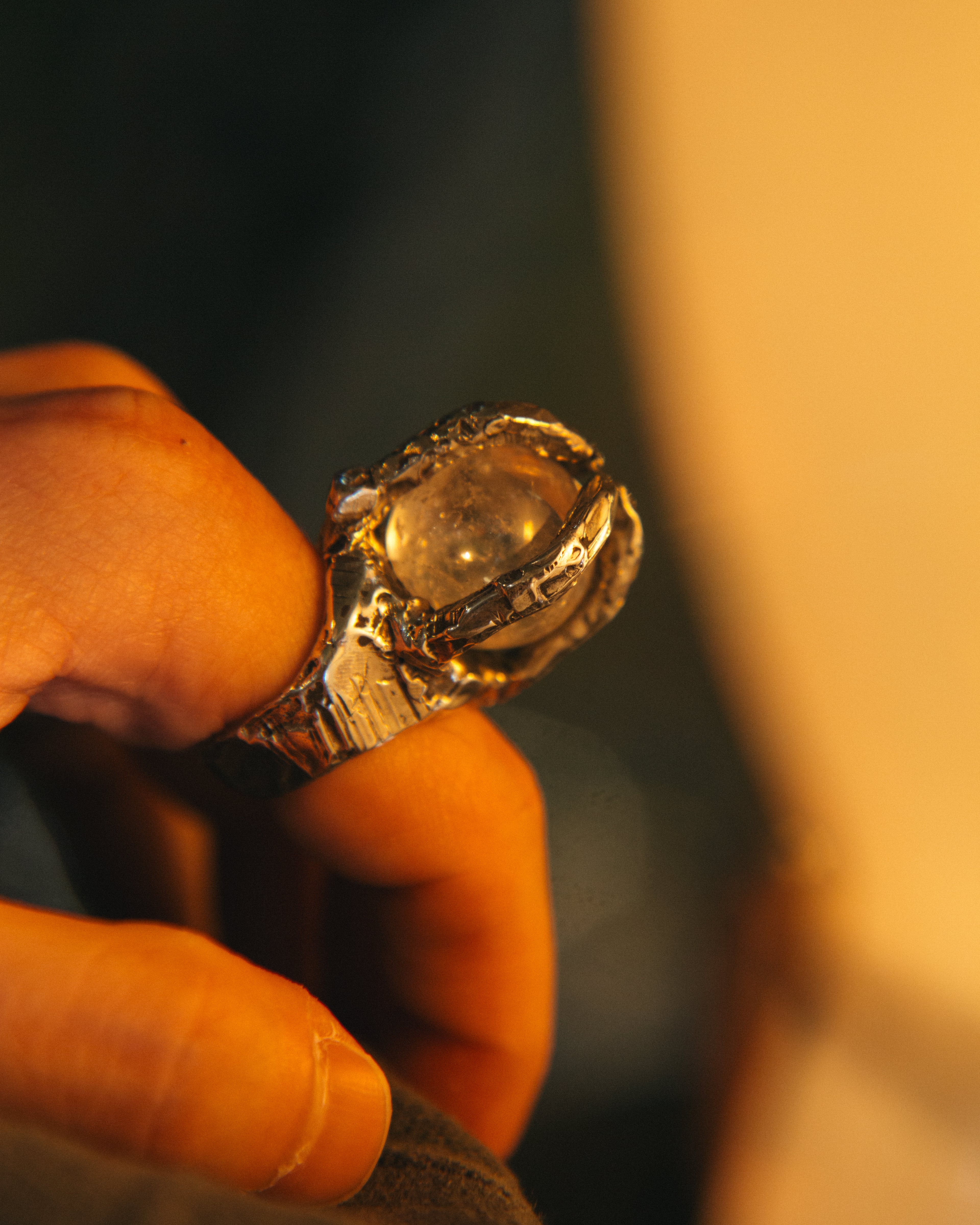 Close-up of a hand holding a decorative ring with a dark background
