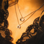 Close-up of a person wearing two necklaces with a black lace garment.