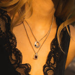 Close-up of a person wearing a black lace top with two necklaces.