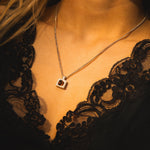 Necklace with a pendant worn by a person in a black lace garment.