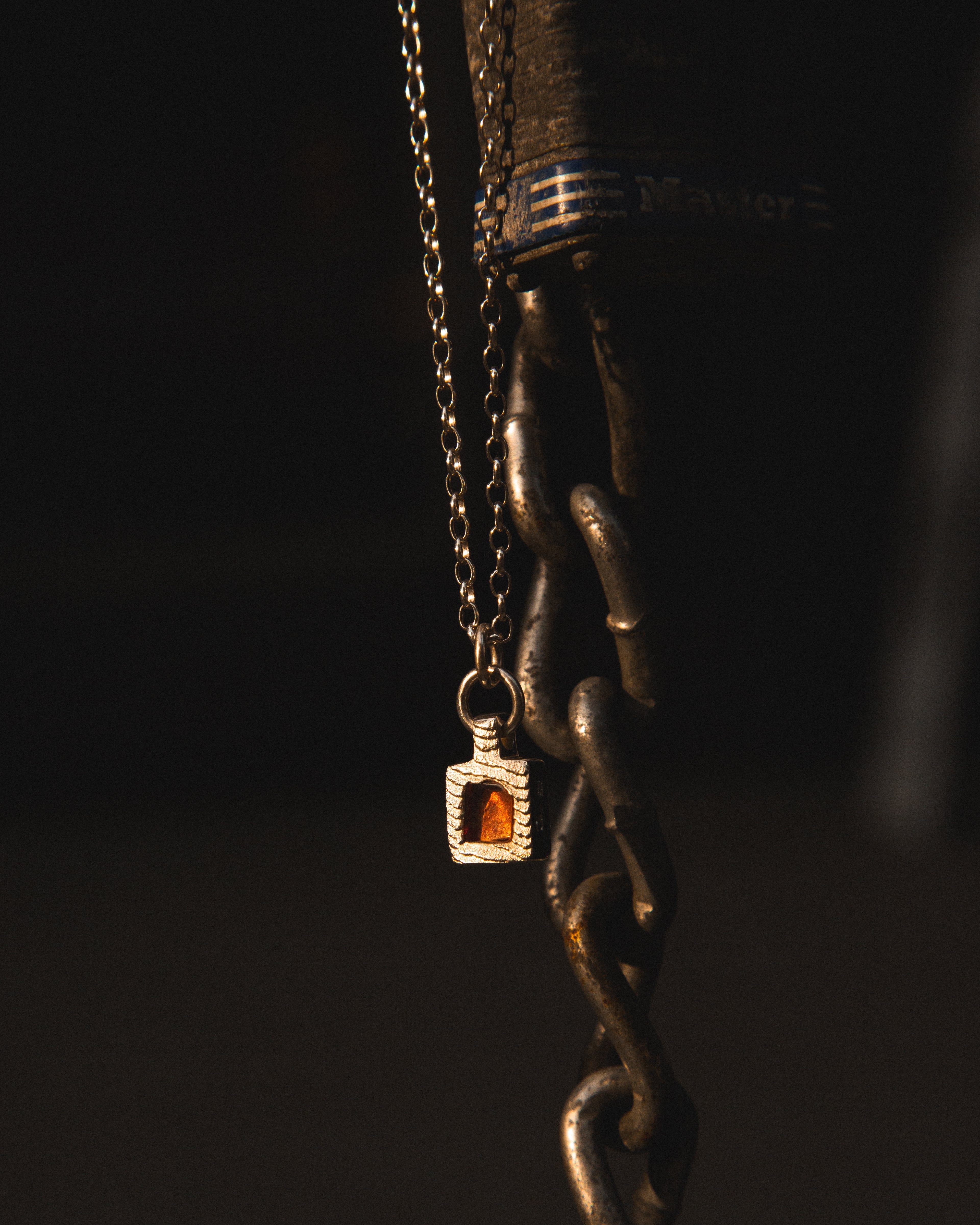 Necklace with a pendant hanging from a chain against a dark background