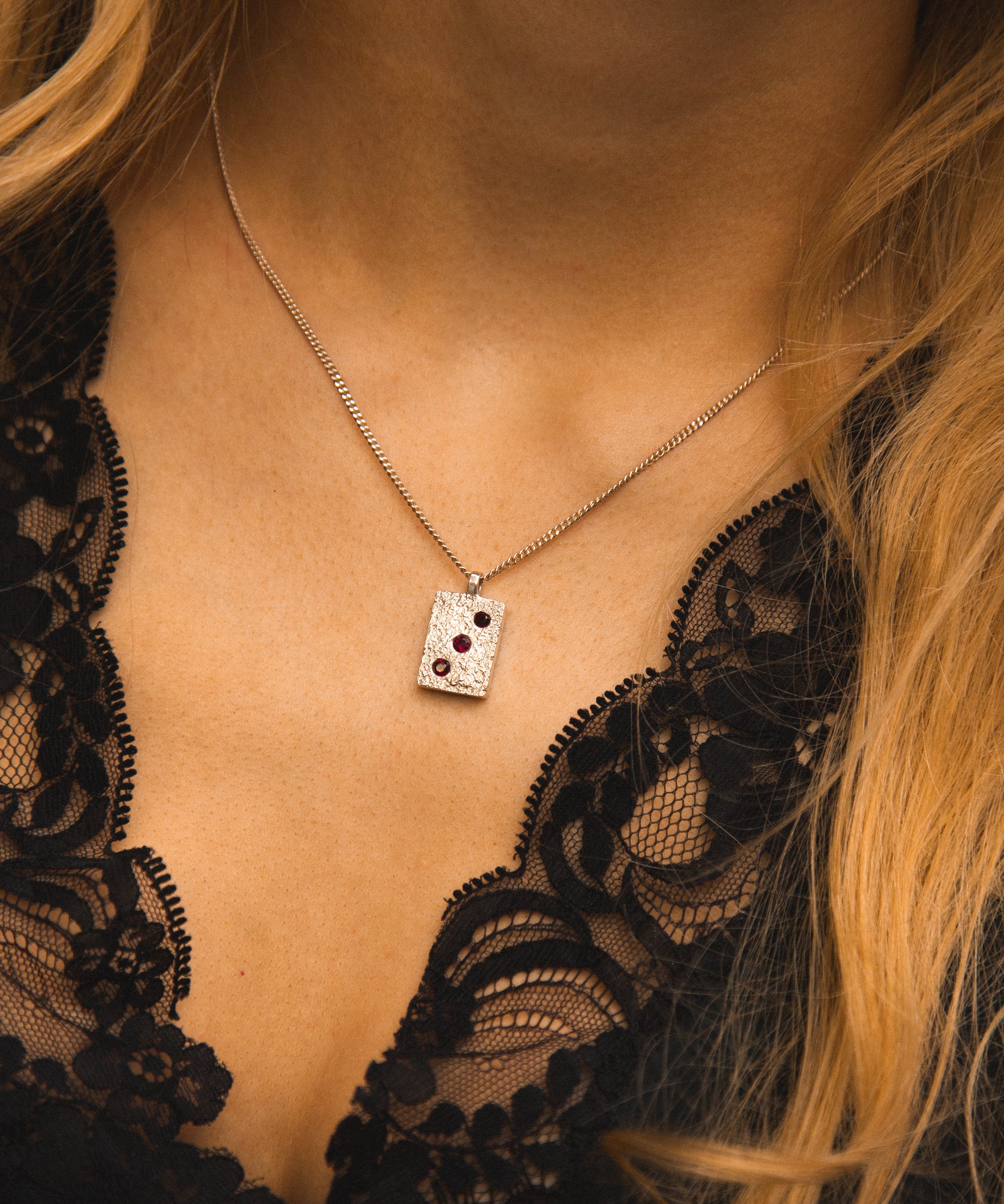 Necklace with a pendant worn by a person in a black lace garment