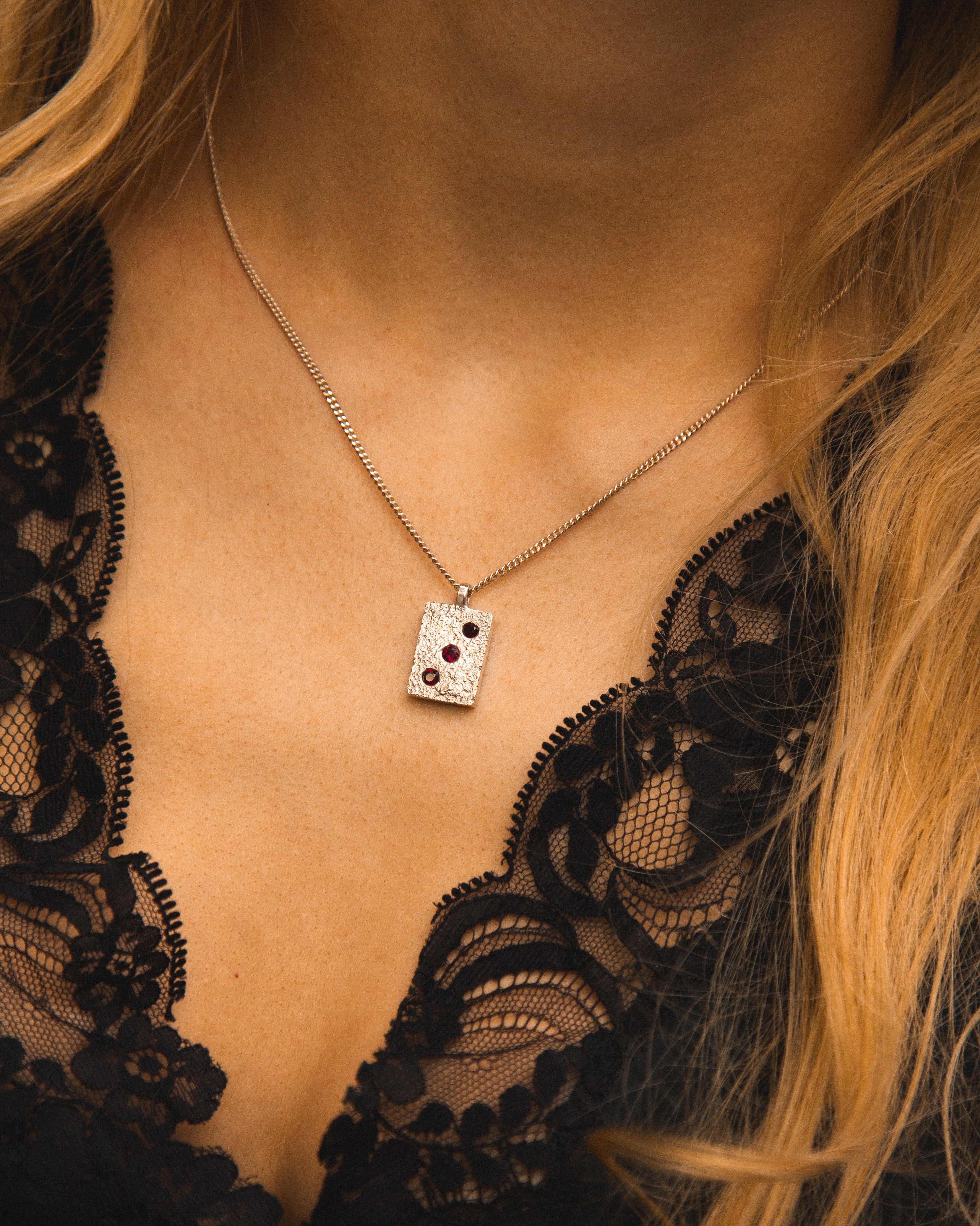 Necklace with a pendant worn by a person in a black lace garment