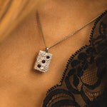 Silver necklace with a pendant worn by a person with black lace garment