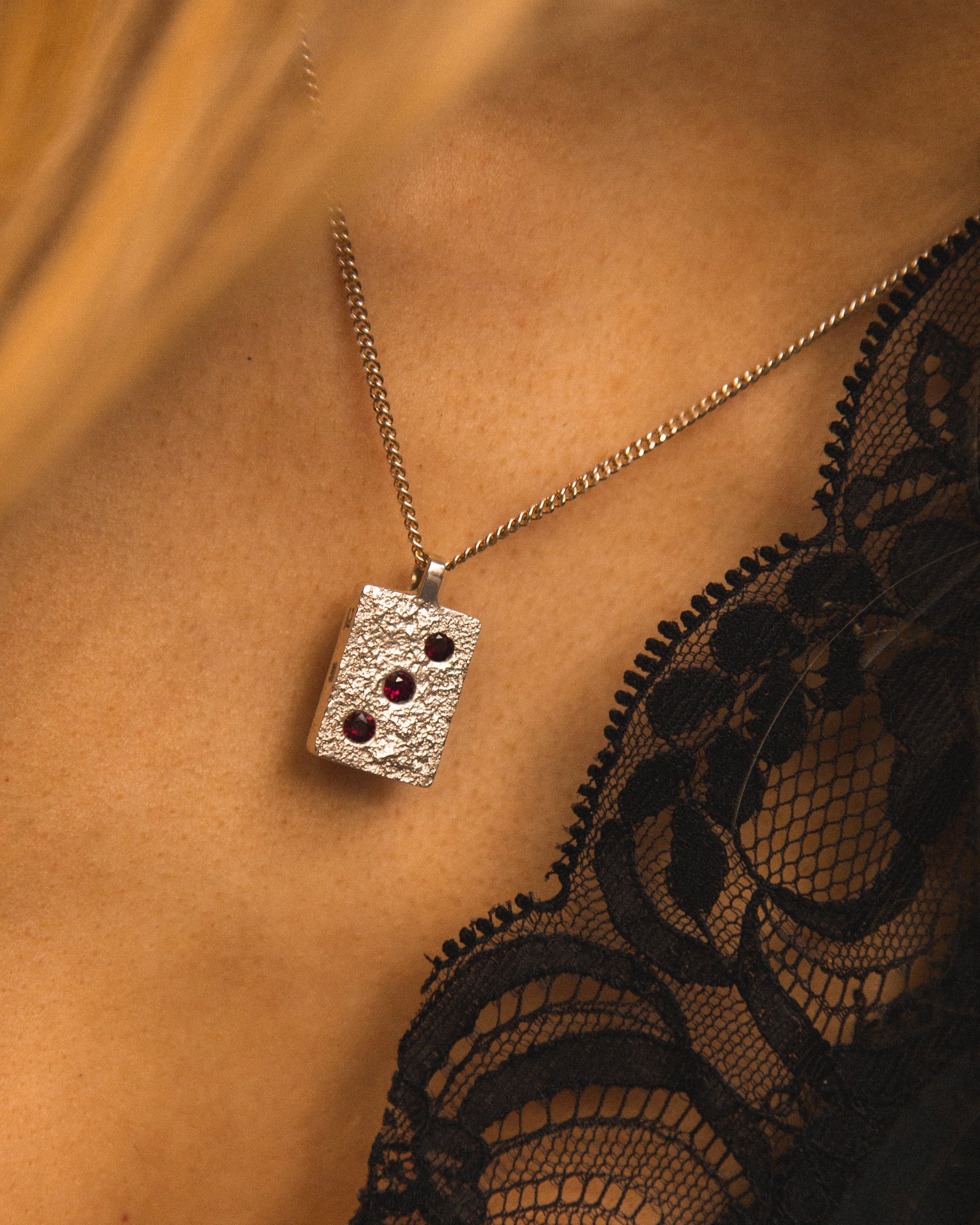 Silver necklace with a pendant worn by a person with black lace garment