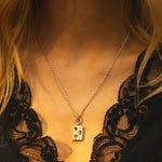 Necklace with a pendant worn by a person in a black lace garment.