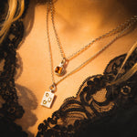 Close-up of a person wearing two necklaces with pendants on a dark background