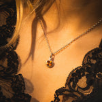 Close-up of a necklace with a pendant on a person wearing a black lace garment.