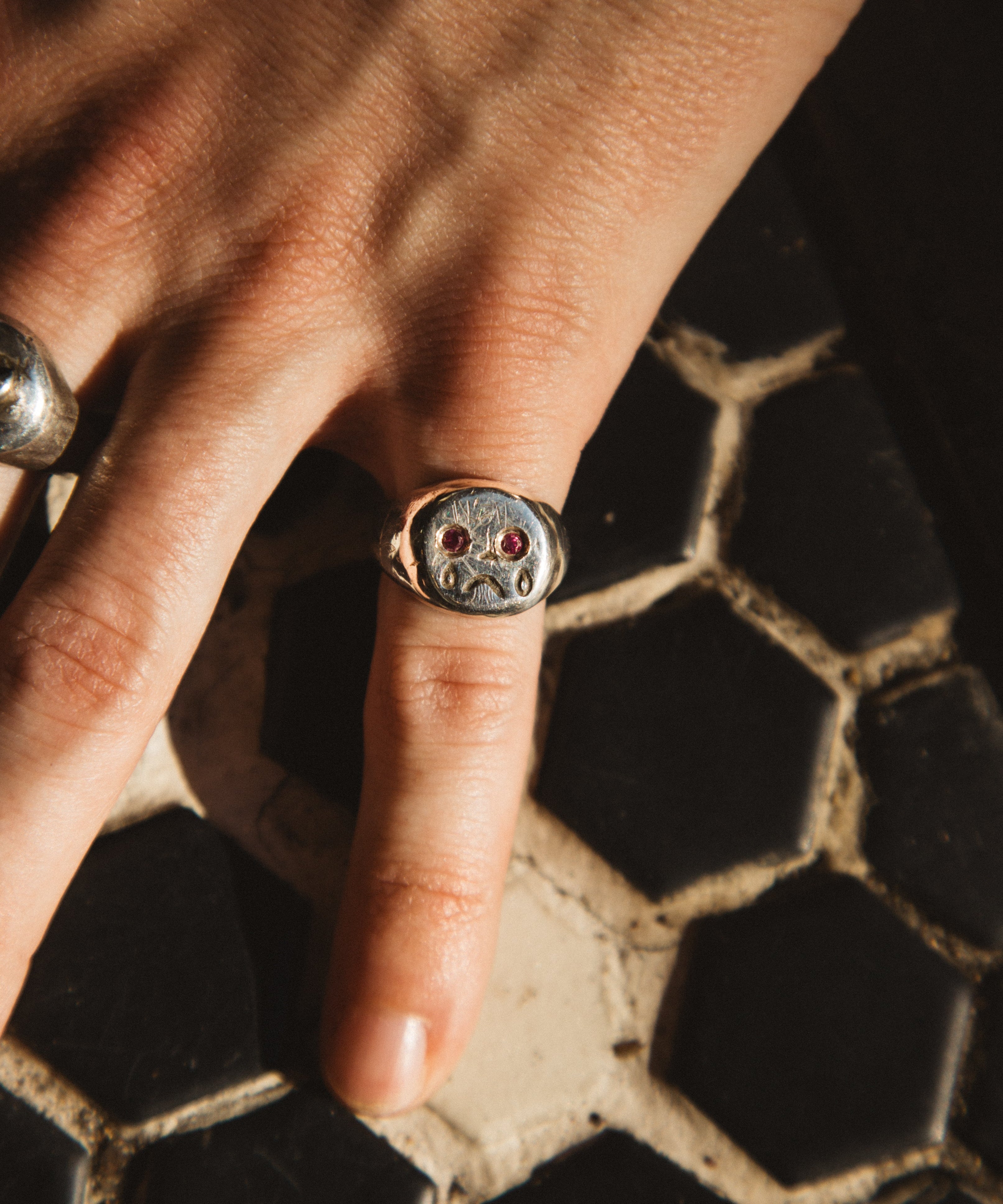 Close-up of a hand wearing a decorative ring on a textured surface