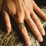 Hand wearing a gold ring on a textured surface