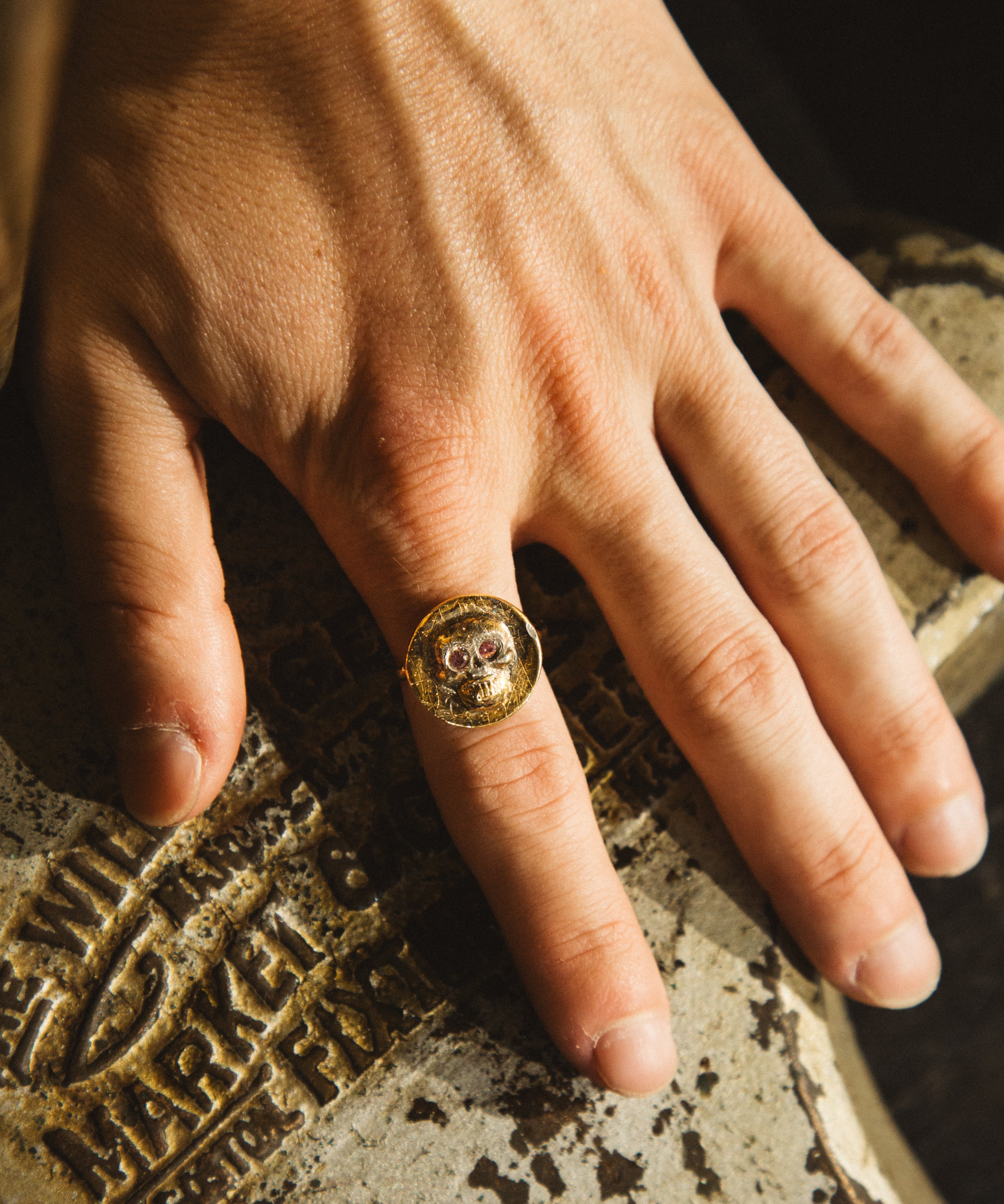Hand wearing a gold ring on a textured surface