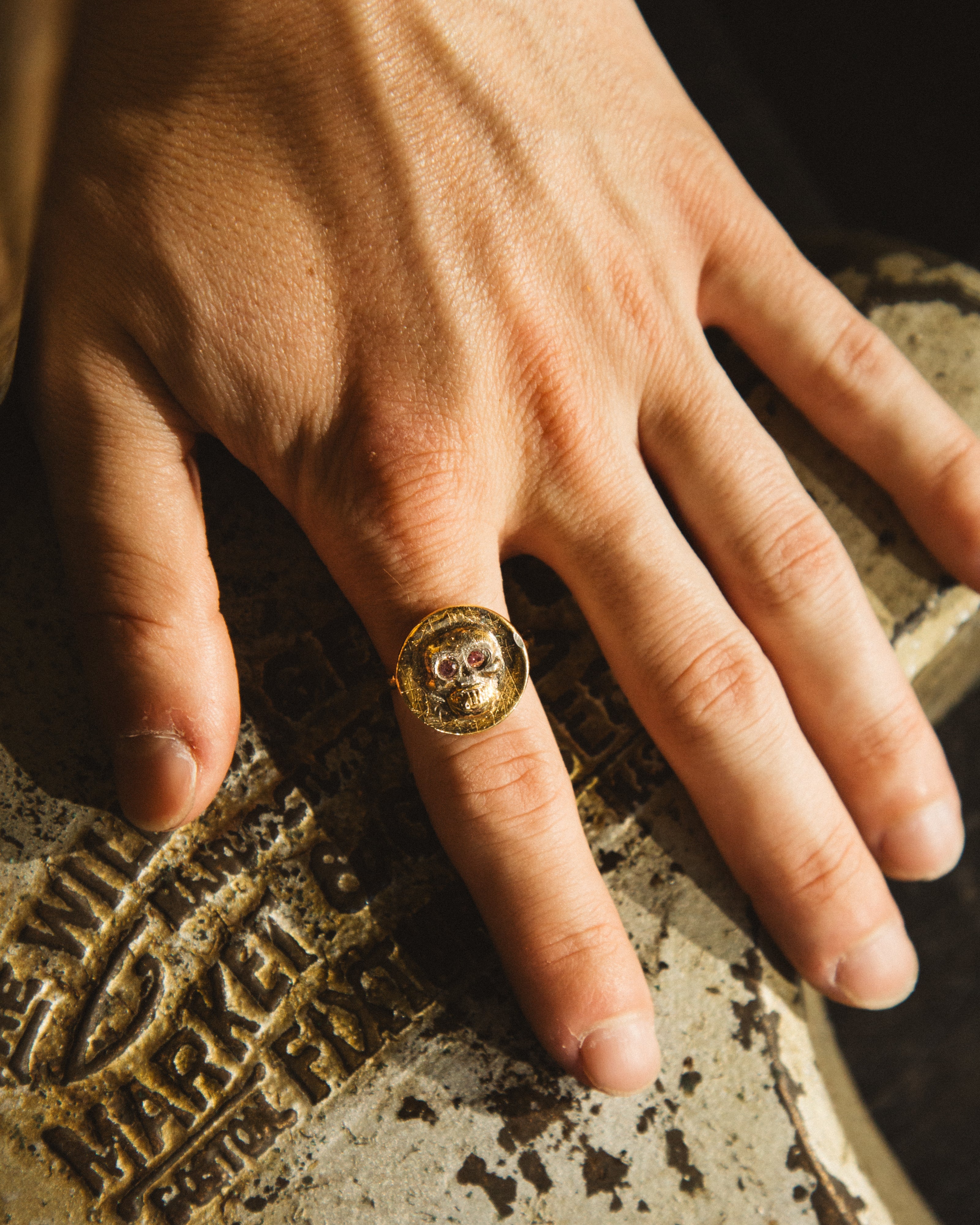 Hand wearing a gold ring on a textured surface