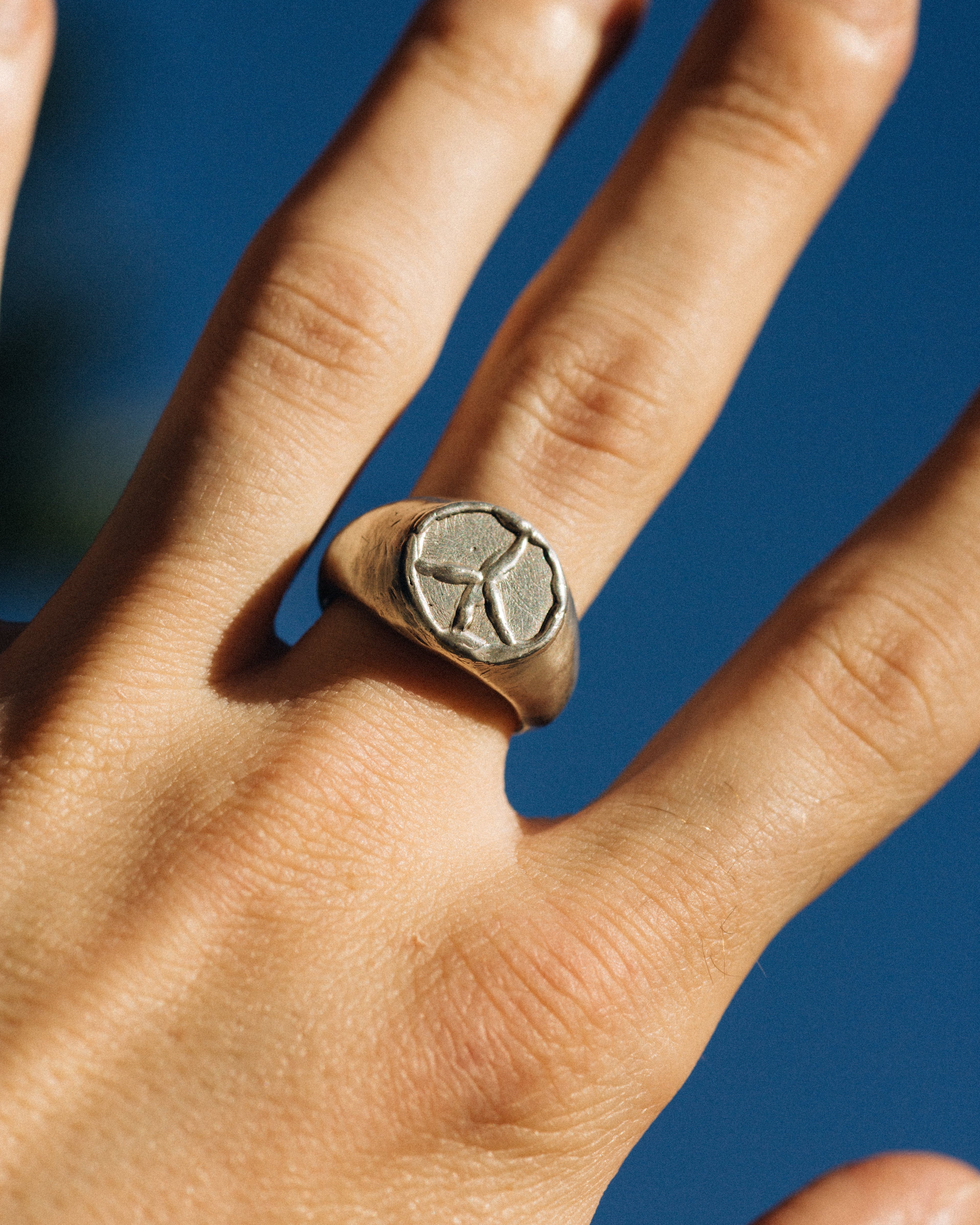 Hand wearing a silver ring with a star design against a blue background