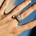 Hand wearing a silver ring with a stone against a blurred blue background