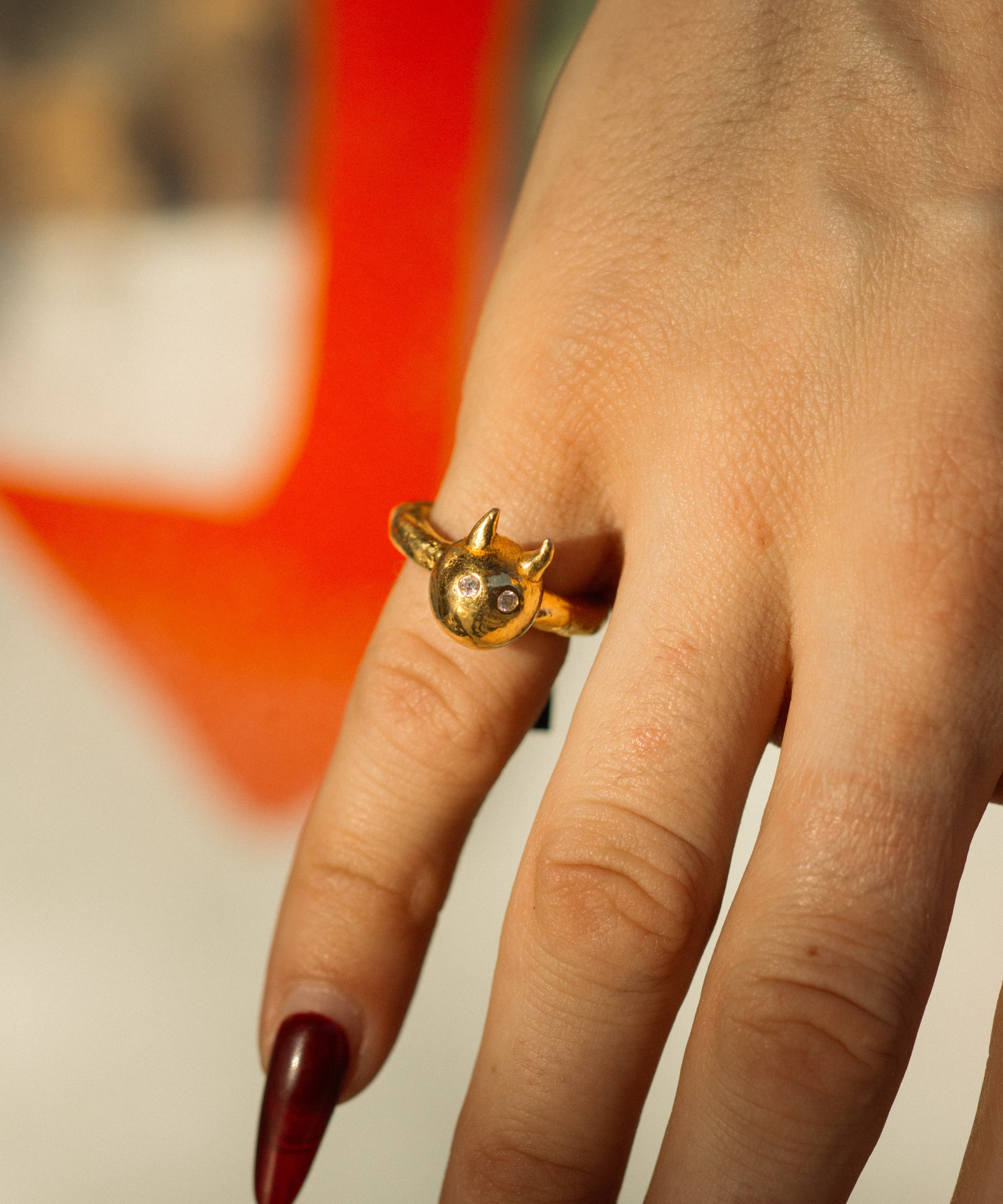 Gold ring with a unique design on a finger against a blurred background