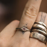 Close-up of a hand wearing two silver rings with a small gemstone on a blurred background